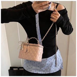 Quilted pink box bag with pearl bow and metal chain strap shown in a mirror selfie