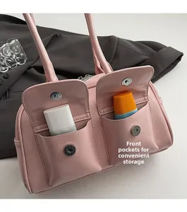 Dettaglio della borsa a spalla rosa lucida con due tasche frontali e chiusure magnetiche