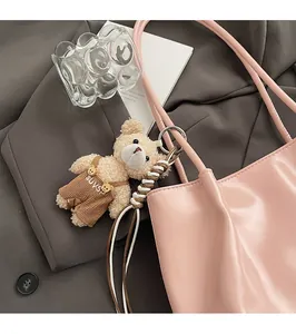 Detailed view of a cute plush bear charm in brown overalls on a pink tote bag