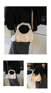 Detail view of cream pleated dumpling bag with ruffle handle and gold chain strap