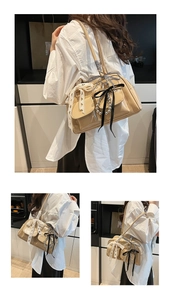 Dettaglio di una borsa Boston in pelle verniciata beige con fiocchi di pizzo e raso