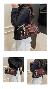 Dettaglio borsa Boston bordeaux con tasche anteriori e ciondolo a fiocco in pizzo