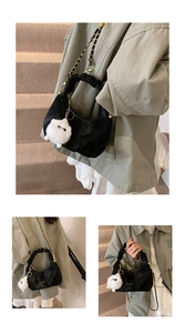 Detail of black pleated crescent bag with gold chain strap and plush monster charm