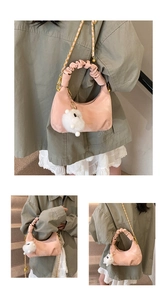 Pink dumpling bag featuring pleated cloud handle, gold chain, and cute bunny charm accessory