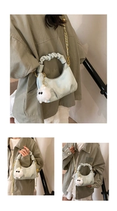 Detail of light mint green pleated handbag with gold chain and plush monster charm
