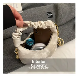 Detail showing the internal capacity of the pleated handbag with makeup and phone