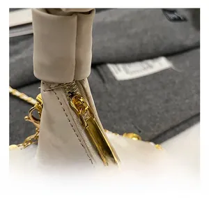 Close-up of golden zipper hardware and pleated beige leather on a croissant bag