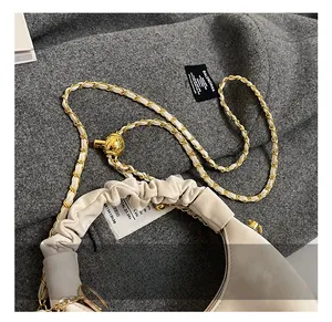 Detail of off-white pleated handbag featuring a gold metal ball slider and chain strap