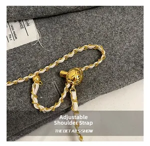 Detail of adjustable gold metal chain strap with woven white leather and golden ball buckle