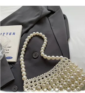 Detailed view of handcrafted white pearl woven handbag on a stylish grey blazer background