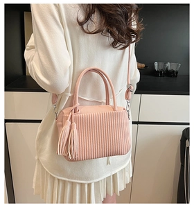 Detail of pink pleated faux leather bag with elegant leather tassel and silver hardware
