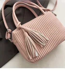 Detail of pink lychee leather bucket bag with vertical pleats and dual tassel charms