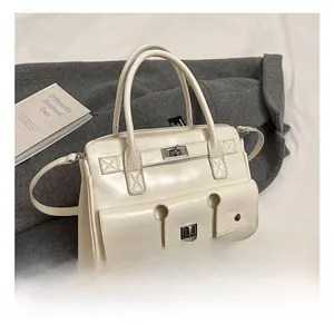 Détail du sac à main en cuir verni crème montrant trois poches frontales et fermoir métal