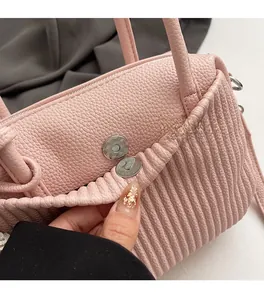 Detail shot of the pale pink lychee leather bag featuring a magnetic snap closure system