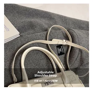 Détail de la bandoulière réglable et de la boucle argentée sur le sac à main beige