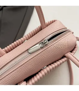 Close-up of smooth silver metal zipper on light pink pebbled leather handbag