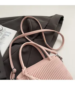 Detail of pink faux leather bag with vertical pleats and sleek shoulder strap hardware