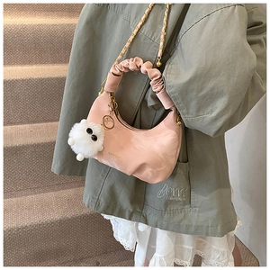 Détail d'un sac demi-lune rose avec poignée froncée et breloque pelucheuse blanche chic