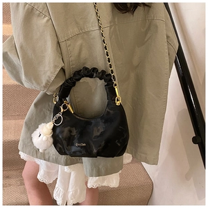 Détail du sac noir avec poignée plissée chaîne dorée et petit mouton en peluche