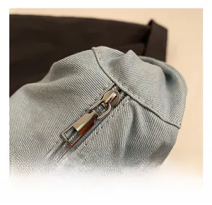 Détail de la fermeture éclair en métal argenté sur un sac fourre-tout en sergé bleu clair