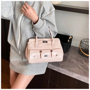 Détail d'un sac à main en cuir verni rose clair avec fermoir rotatif argenté et anses