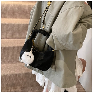 Detail of black pleated hobo bag with gold chain strap and cute plush cat charm decoration