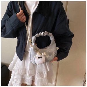 Détail du sac croissant plissé argenté avec bandoulière dorée et breloque mouton