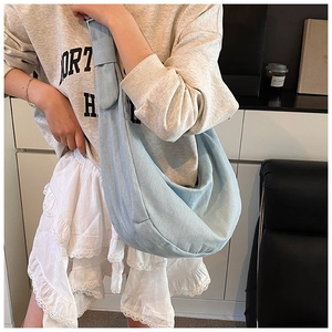 Détail du sac hobo en denim bleu clair montrant sa grande capacité et sa texture décontractée