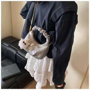 Detail of grey pleated cloud bag with gold chain strap and fluffy monster charm