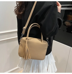 Détail du sac à bandoulière plissé beige avec de longs glands et une bandoulière amovible