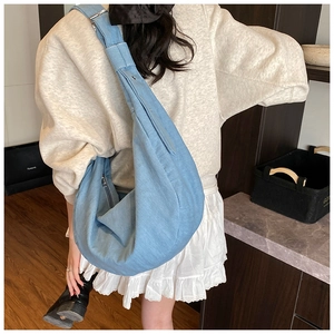 Détail d'un sac bandoulière en denim bleu clair avec fermeture éclair et bandoulière