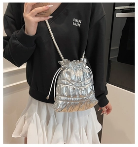 Detail of silver metallic drawstring bucket bag with pearl strap and bow accents