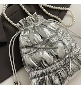 Close-up of silver quilted drawstring bag with glossy texture and pearl beaded strap