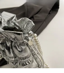 Close-up of metallic silver drawstring bag featuring pearl strap and gathered texture