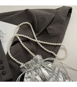 Macro detail of silver pleated metallic drawstring bucket bag with pearl strap