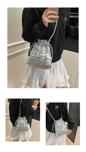 Detail of silver metallic drawstring bucket bag with pearl strap and bow accent