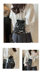 Close-up of black glossy drawstring bucket bag featuring pearl straps and bow details