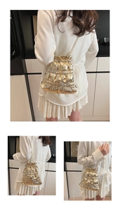 Detail of golden pleated bucket bag with pearl strap and bow accents shown on model
