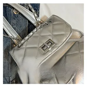 Detail of silver quilted texture with metallic chain strap and turn-lock closure on bag