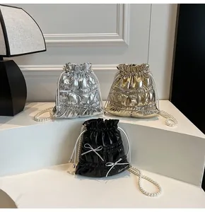 Close-up of metallic bucket bags with drawstring bows and pearl chain straps