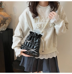 Detail of black pleated drawstring bag with pearl strap and silver bow accents