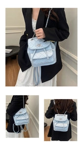 Detail of light blue quilted backpack with silver clasp and woven chain straps