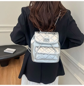 Detail of silver quilted mini backpack featuring metallic texture and chain straps