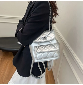 Detail of silver quilted mini backpack with metal chain strap and turn-lock closure
