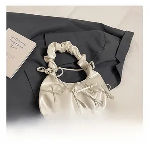 Detailed close-up of cream PU leather handbag with decorative bows and ruched handle