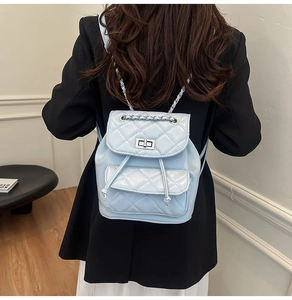 Detail of light blue quilted faux leather backpack with silver chain strap and metal lock