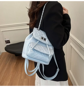 Close-up of light blue quilted PU leather backpack with silver chain straps on model
