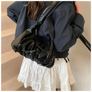 Close-up of black pleated underarm bag with bow details and wide shoulder strap style