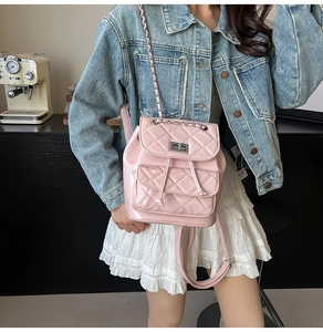 Pink quilted leather backpack with metal chain straps shown on a model in casual style