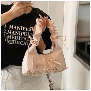 Close-up of pleated handle and delicate ribbon bows on a pastel pink hobo bag